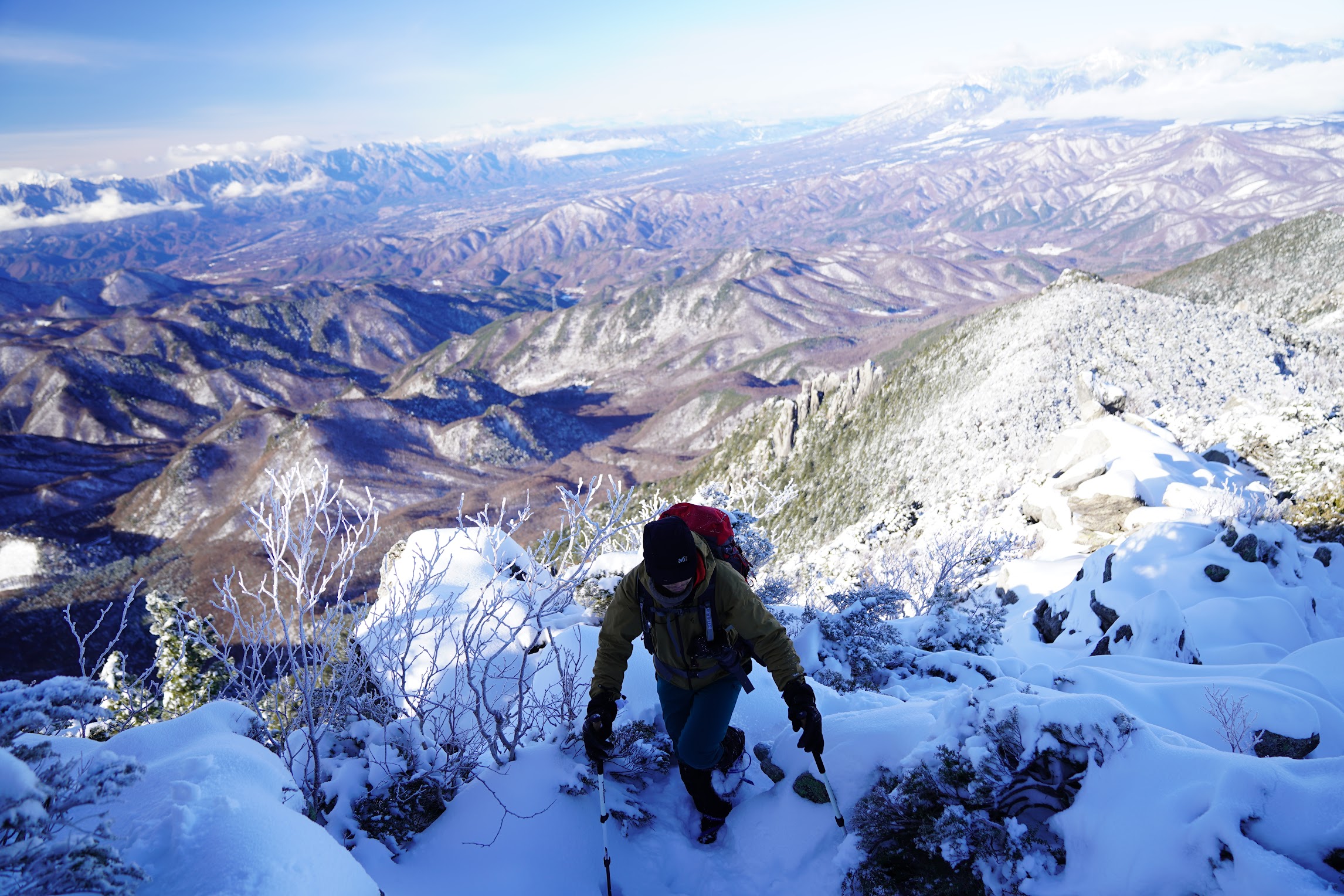 冬の登山を楽しんでいるウェブディレクターの写真。背後に広がる絶景が圧巻。